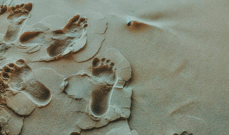 Footprints in sand symbolising relief after successful ingrown toenail treatment.